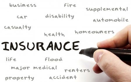 Insurance being written with a black marker on a dry erase board by a hand with other terms such as business, fire, car, health, homeowners, disability and more
