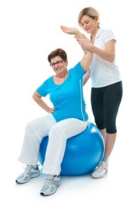 Senior woman doing fitness exercise with help of trainer at sport gym