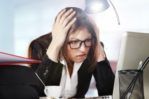 A young businesswoman is looking stressed as she works at her computer