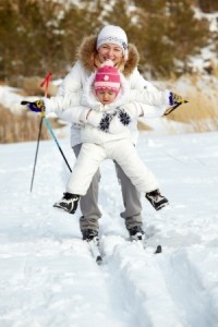 Little girl and her mother skiing in park