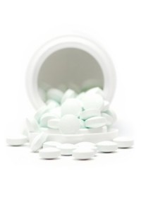 White tablets out of a plastic box. Isolated on a white background. Shallow depth of field.