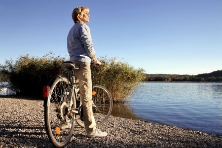 Woman riding a bike beside a lake