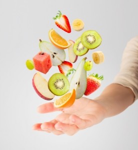 Assorted fresh fruits flying in a hand