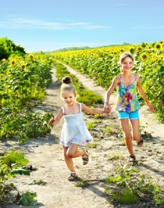Group children running across sunflower field outdoor.