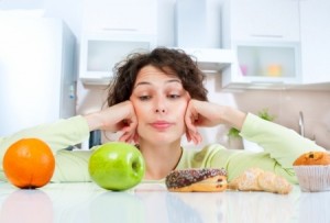 Dieting concept Young Woman choosing between Fruits and Sweets