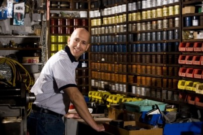 Man standing in front of colored inks in print shop