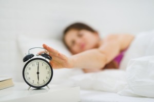 Closeup on woman hand reaching to turn off alarm clock
