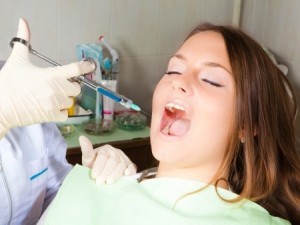 dentist hand holding a syringe, making a numb shot for woman patient, horizontal shot
