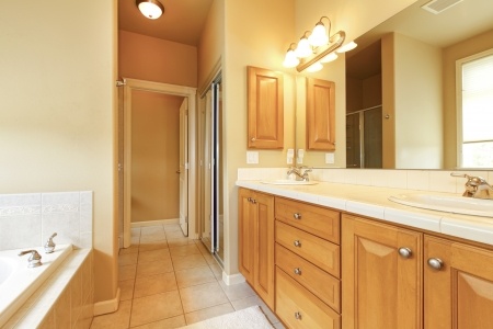 Bathroom interior with beige tiles and wood cabinets
