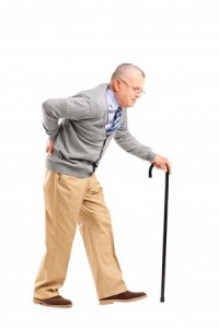Full length portrait of a senior gentleman walking with cane and suffering from back pain isolated on white background