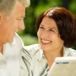 Happy smiling attractive senior couple reading together, outdoors