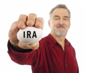 Mature man holds a white nest egg with IRA on it.