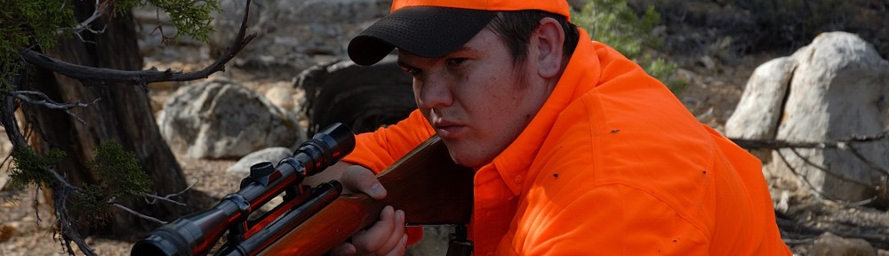 Rifle hunter prepares to take a shot at deer.