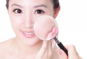 Check your health skin! young asian woman with perfect skin and magnifying glass check it isolated on white background, concept for skincare