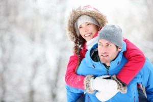 Man giving woman piggyback ride on winter vacation in snowy forest
