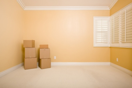 Moving Boxes in Empty Room with Copy Space on Blank Wall.