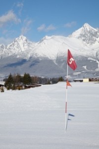 Red flag in hole at snow covered golf field