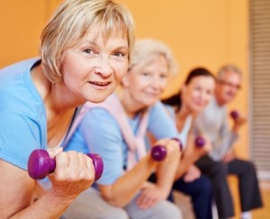 Senior woman with dumbbells doing back training in a fitness center