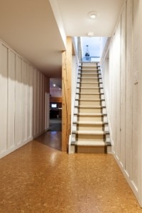 Stairway to finished basement in home interior with wood paneling and cork flooring