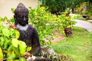 Statue of Buddha holding flowers in a garden