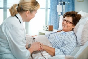 doctor or nurse talking to patient lying in bed in hospital
