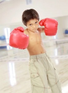 portrait of happy young kid with boxing glove ready to fight in the gym