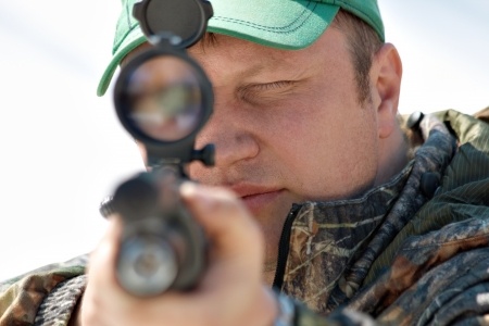 Close up hunter aiming with weapon at the outdoor hunting