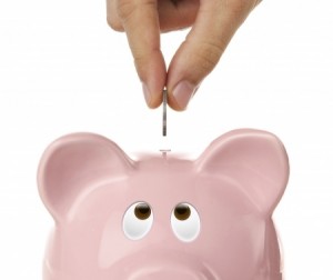 Male hand putting coin into a piggy bank