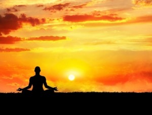 Yoga meditation in lotus pose by man silhouette at sunset sky background