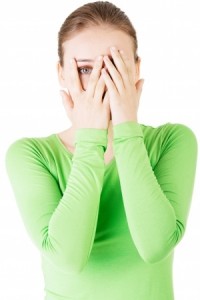 Attractive woman covering her face with both hands. Isolated on white