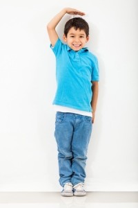 Boy growing tall and measuring himself on the wall