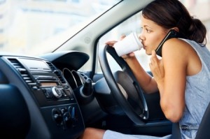 Businesswoman multitasking while driving, drinking coffee and talking on the phone