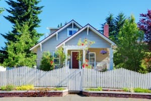 Cute small grey old craftsman style house with white fence.