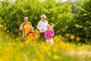 Happy Family with two girls running or jogging for sport and better fitness in a meadow
