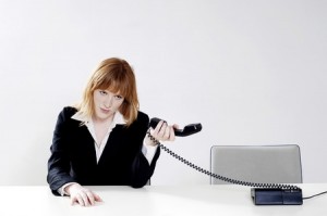 Businesswoman holding phone receiver away from her ear