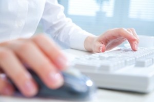 Detail of female hands using a computer on office background