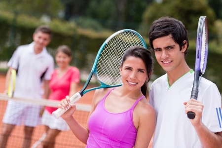 Happy tennis couple playing doubles at the court
