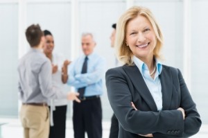 Portrait Of Happy Senior Businesswoman In Office With Her Colleagues