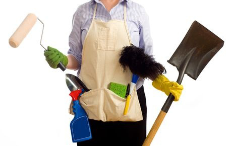 A woman with various spring cleaning and redecorating items including a paint brushes, garden tools, cleaning chemicals and items. Spring time chores