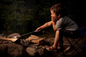 Little boy cooking a marshmallow over a campfire at night