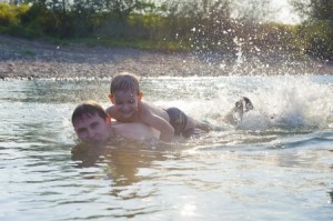 Young father and his little son swimming in river