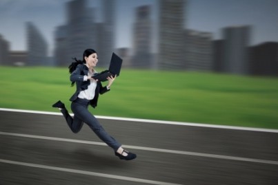 Asian businesswoman running and holding a laptop on the track
