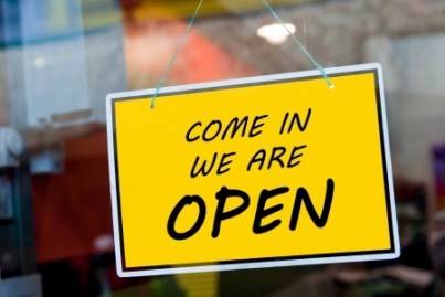 come in we are open sign hanging on a window