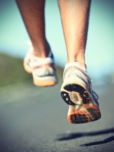 Running shoes on runner - closeup of sport shoes outdoors on man runner during run