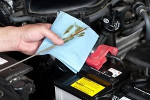 An auto mechanic checks the oil level in a car engine during routine maintenance