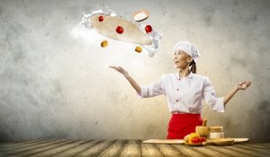 Asian female cook making pizza standing against color background