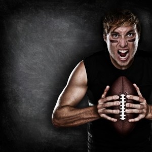 Football player aggressive portrait holding american football on black blackboard background with copy space for text or design