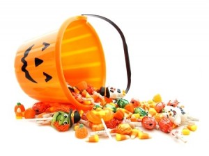 Halloween jack-o-lantern pail with spilling candy over white