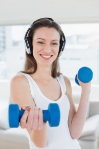 Portrait of a fit young woman exercising with dumbbells in bright fitness studio
