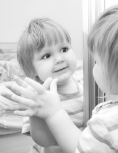 A girl looks in the mirror. Black and White image of baby.
